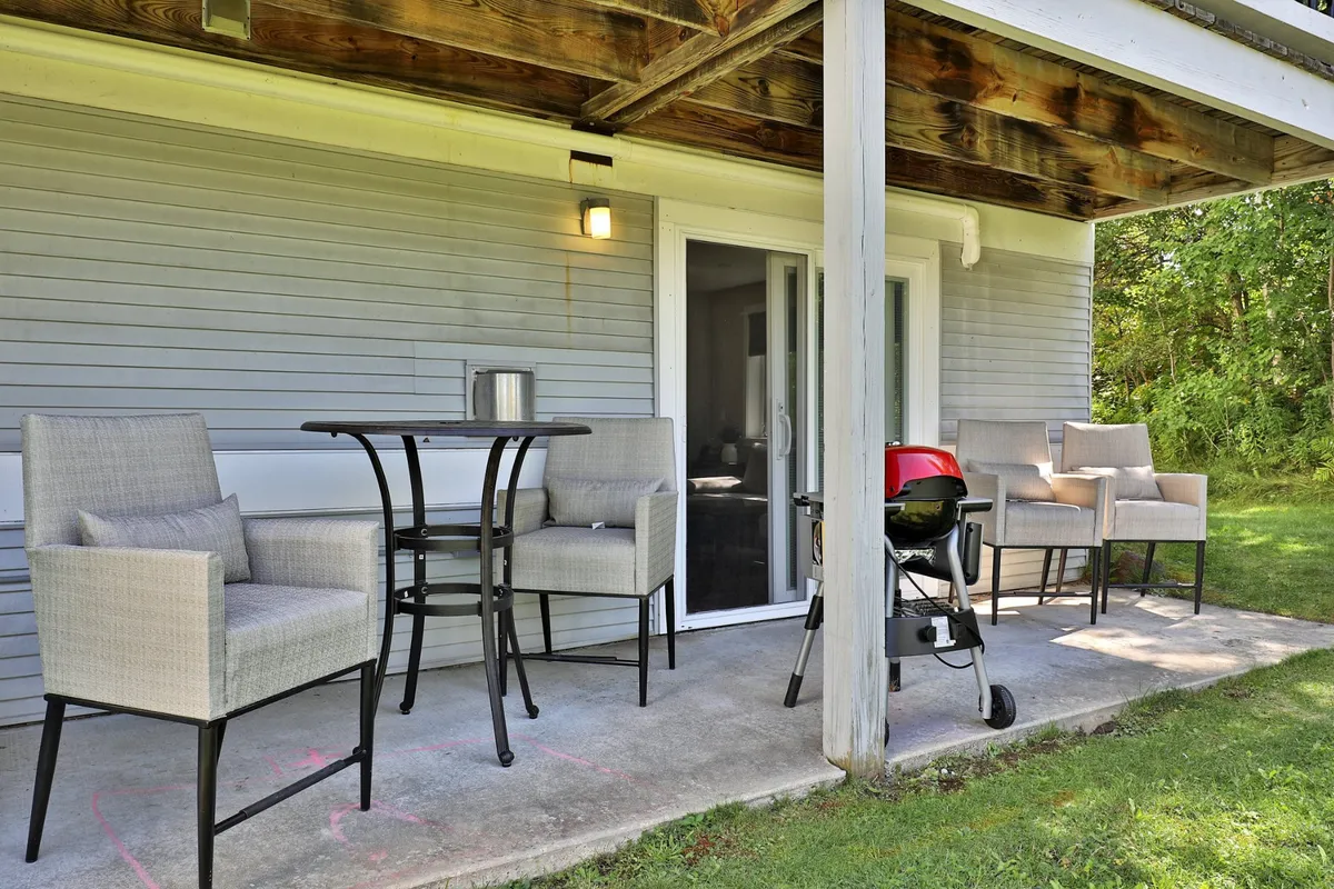 A private outdoor patio featuring comfortable patio furniture, an electric grill, and a sliding glass door connecting directly to the interior. The setting is ideal for alfresco dining, barbecues, or soaking up the sunshine.