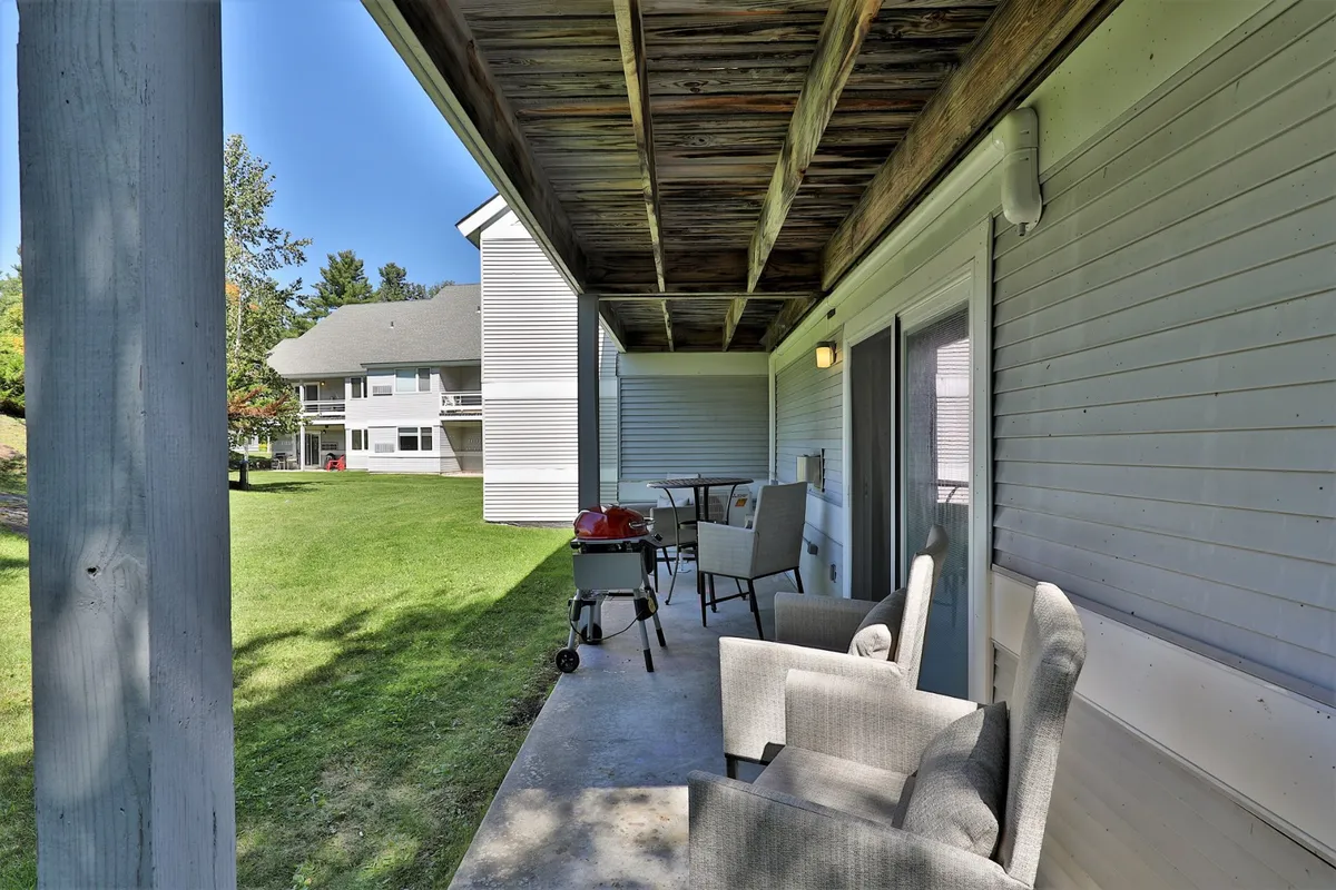A welcoming patio area with a barbecue grill, table and chairs, and a lush green lawn. The comfortable seating and greenery set the stage for enjoying meals outdoors, whether it's a family barbecue, morning coffee, or afternoon relaxation.