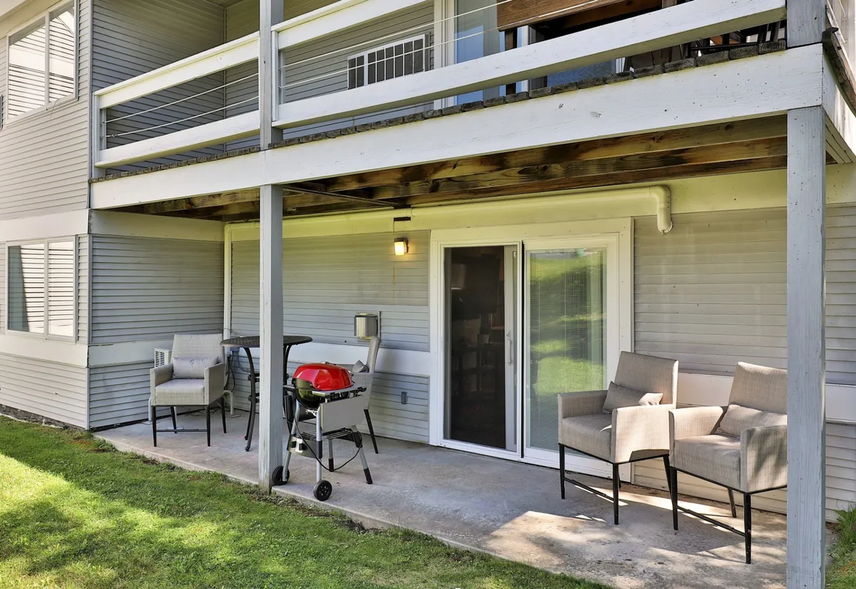 This image showcases an inviting outdoor seating area with a barbecue grill and a sliding glass door leading back inside the property. The setup suggests a relaxed, social atmosphere ideal for gatherings with friends or unwinding after a night out.